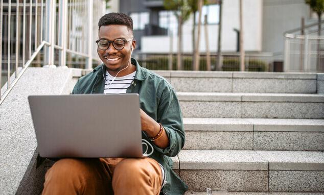 Man in headphones sitting on stairs with a laptop